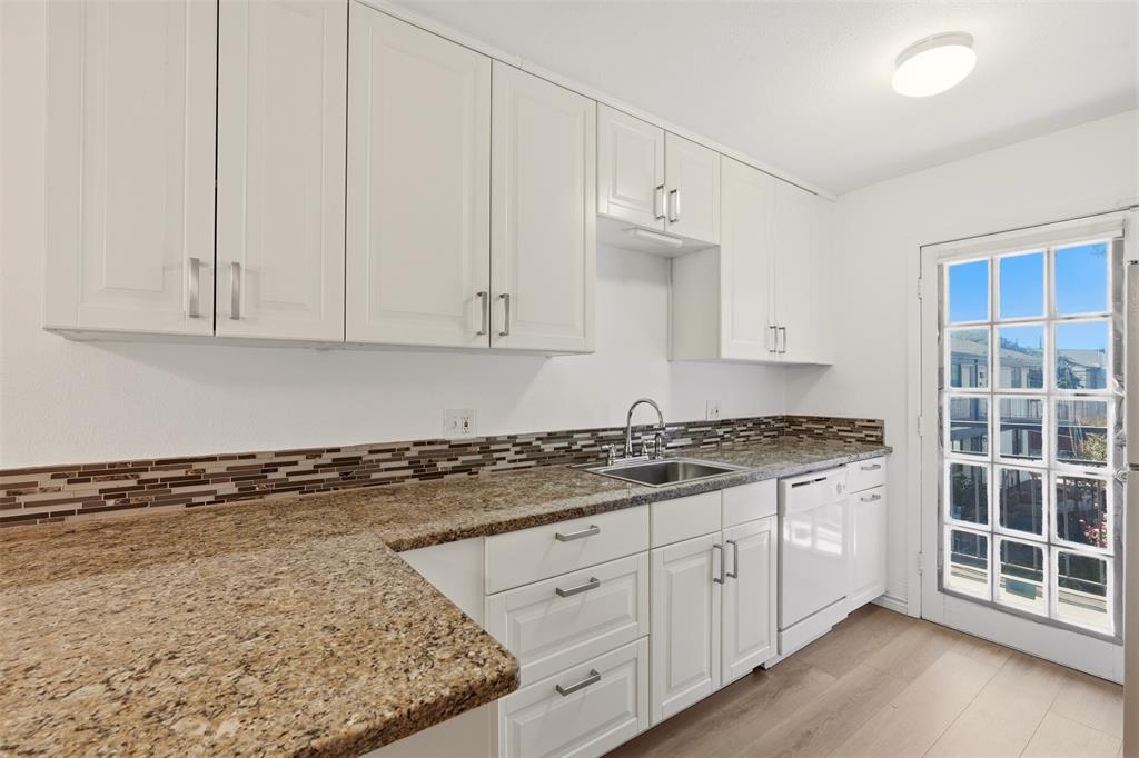 White cabinetry with brushed nickel hardware, granite-style countertops, mosaic tile backsplash, stainless steel sink, and wood-finish flooring