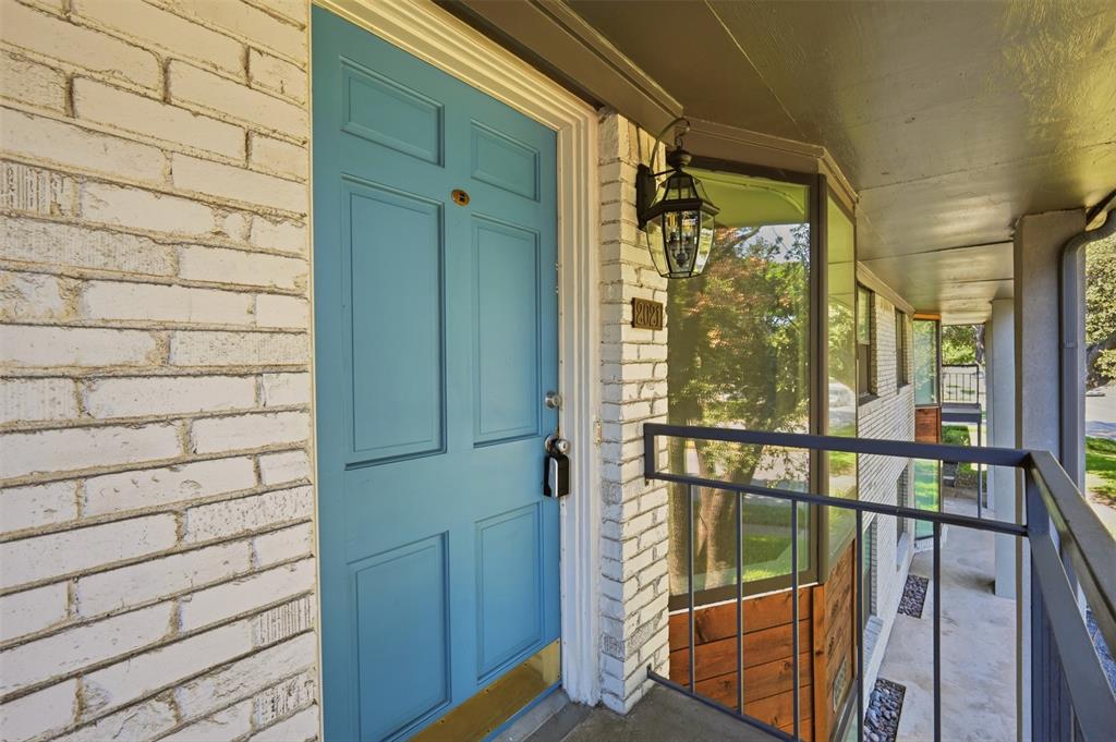 White brick exterior with a panelled turquoise entry door, complemented by a black lantern-style sconce and a dark metal balcony railing White brick exterior with a panelled turquoise entry door, complemented by a black lantern-style sconce and a dark metal balcony railing