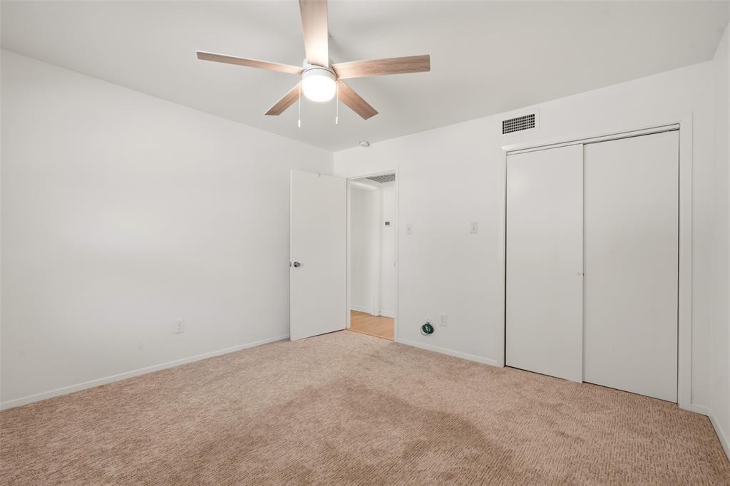 Carpeted flooring with a ceiling fan light fixture and sliding closet doors