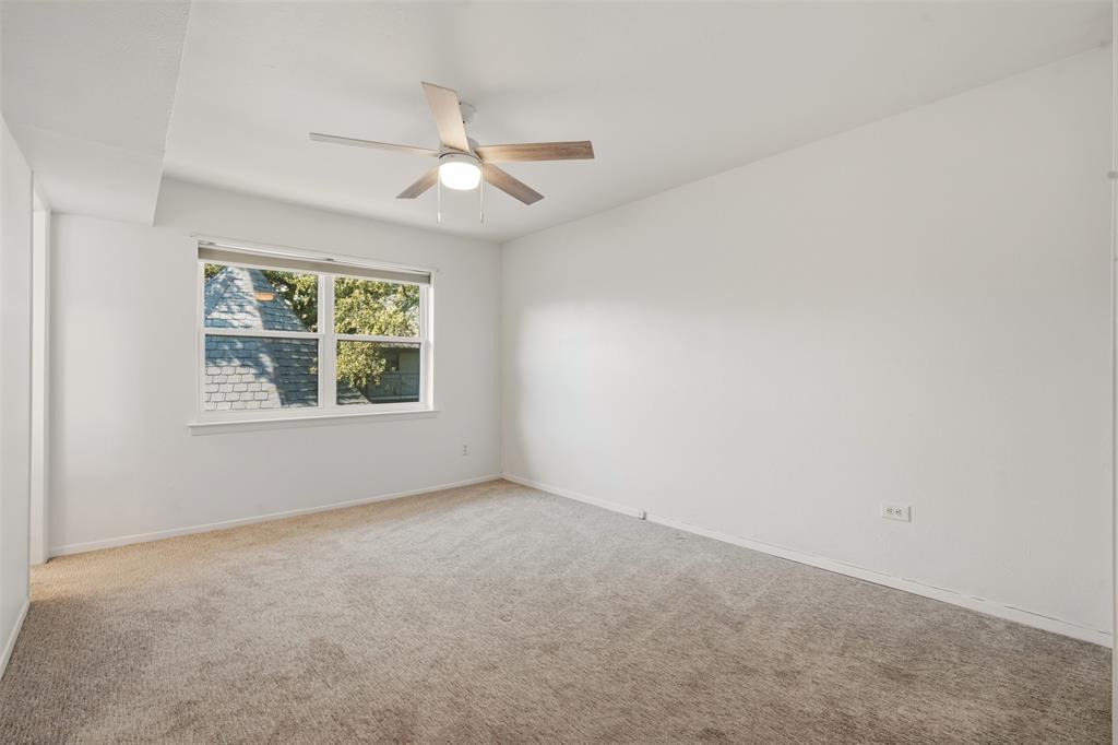 Carpeted flooring, white painted walls, white trim, window with roller shade, and a ceiling fan with integrated lighting