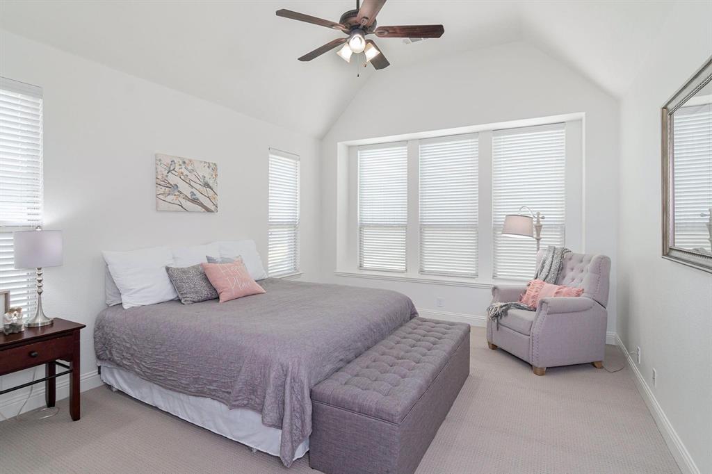 Vaulted ceiling with a ceiling fan, multiple windows with blinds, and light-toned carpeting