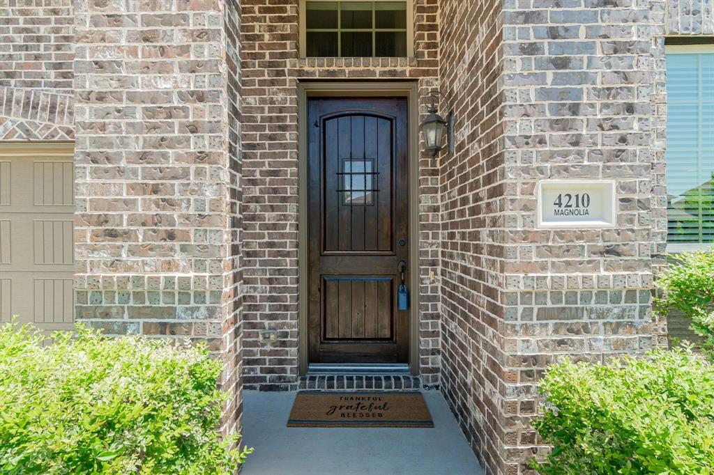 Brick exterior with an arched entryway, featuring a dark wood door with glass inserts and an exterior wall lantern