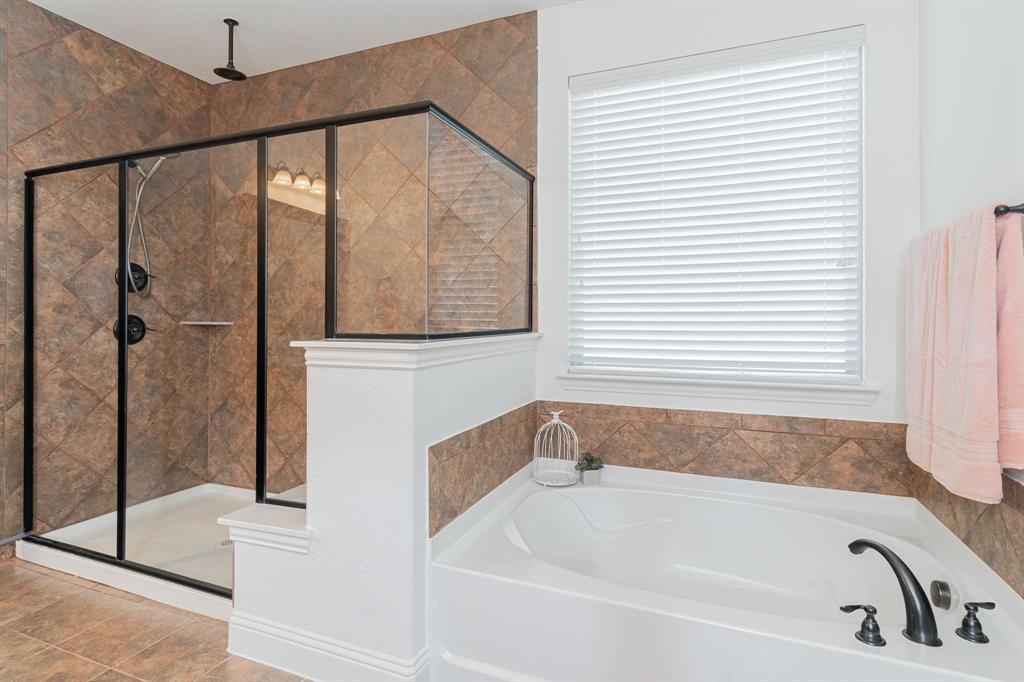 Walk-in shower with black-framed glass enclosure, built-in shower shelf, and ceiling-mounted rain shower head