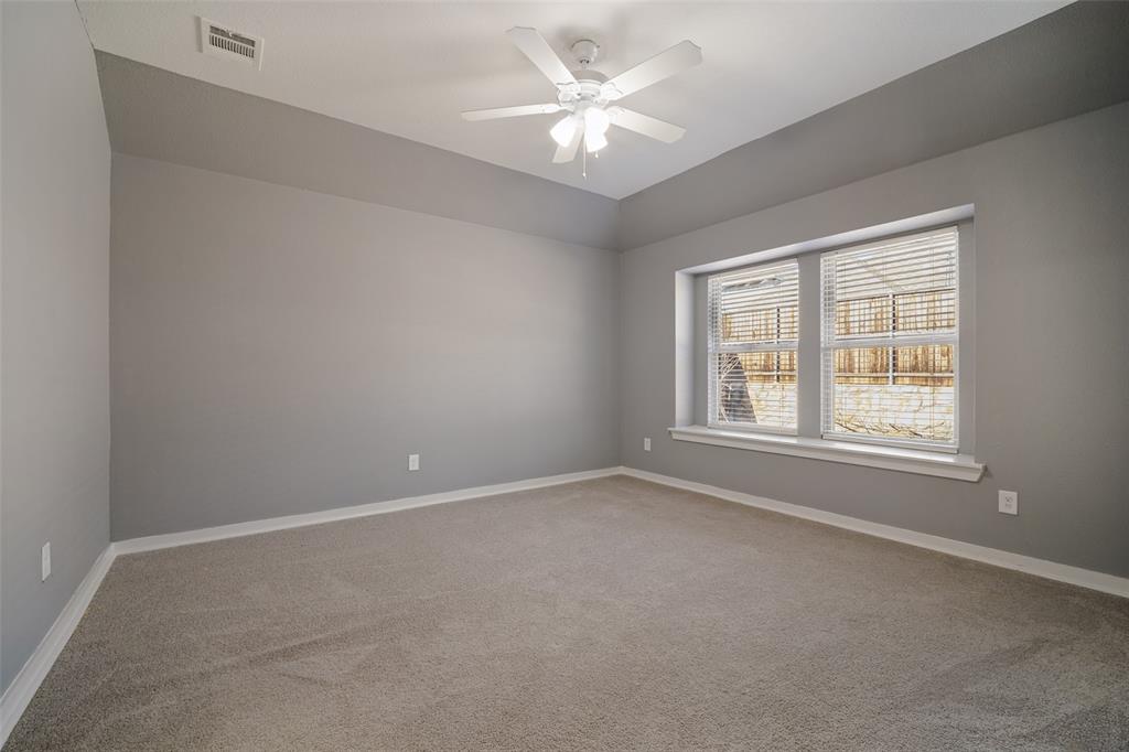 Room featuring neutral carpeting, tray ceiling, multi-blade ceiling fan with integrated lighting, and a dual-pane bay window