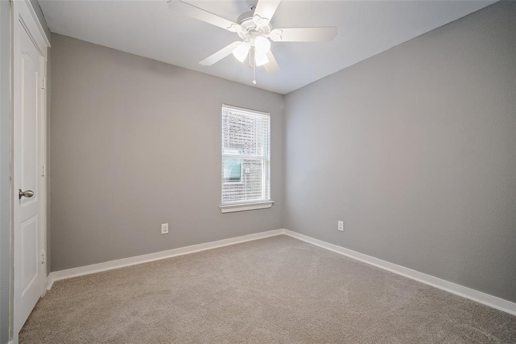 Neutral-toned interior featuring wall-to-wall carpeting, a white ceiling fan with integrated lighting, a single window with horizontal blinds, and a paneled interior door