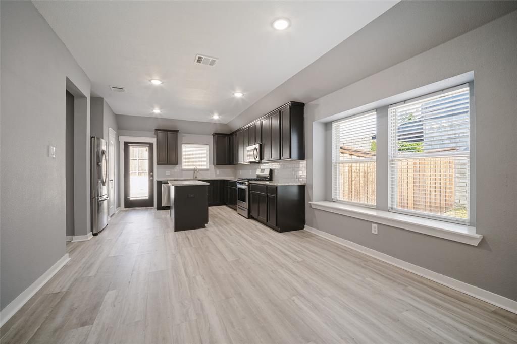 Kitchen featuring dark cabinetry, center island, light-toned wood-finish flooring, recessed lighting, and a window seat Kitchen featuring dark cabinetry, center island, light-toned wood-finish flooring, recessed lighting, and a window seat