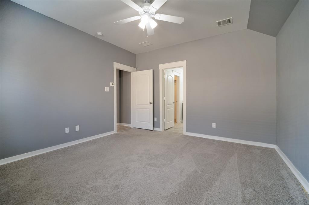 Vaulted ceiling featuring a central ceiling fan with integrated lighting, neutral wall paint, and wall-to-wall carpeting