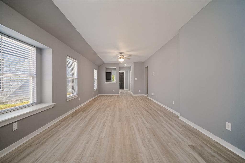 Spacious interior featuring wood-finish flooring, recessed windows with built-in sills, and a centrally mounted ceiling fan with integrated lighting Spacious interior featuring wood-finish flooring, recessed windows with built-in sills, and a centrally mounted ceiling fan with integrated lighting
