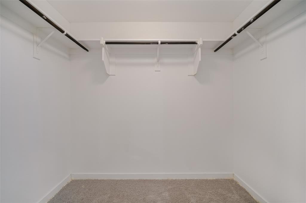 Walk-in closet featuring white walls, carpeting, and multi-tiered shelving with hanging rods