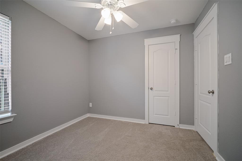Room featuring wall-to-wall carpeting, neutral interior paint, a ceiling fan with integrated lighting, and two multi-panel interior doors