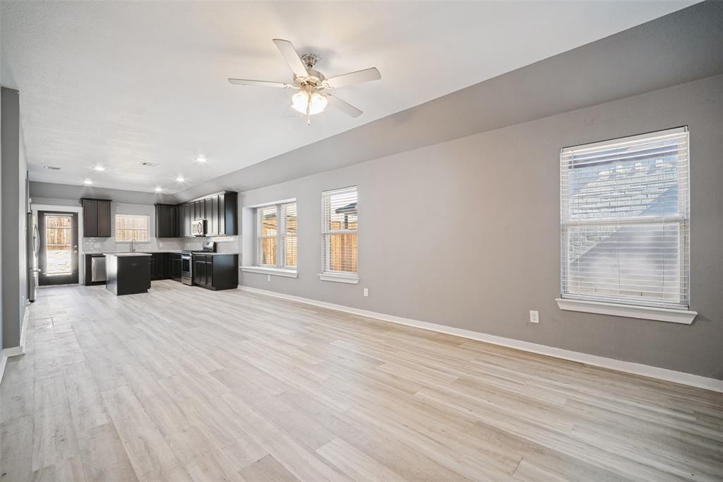Open-concept interior featuring wood-finish flooring, dark cabinetry, a central kitchen island, recessed lighting, and a ceiling fan Open-concept interior featuring wood-finish flooring, dark cabinetry, a central kitchen island, recessed lighting, and a ceiling fan