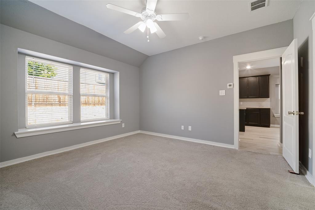Neutral-toned room featuring a vaulted ceiling, bay window with sill, carpeted flooring, and a ceiling-mounted fan with light fixture