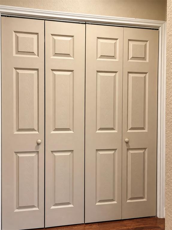 Bi-fold doors with panel detailing, white trim, and wood-finish flooring