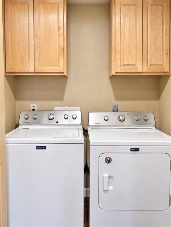 Laundry area with light wood-finish cabinetry and a neutral wall color