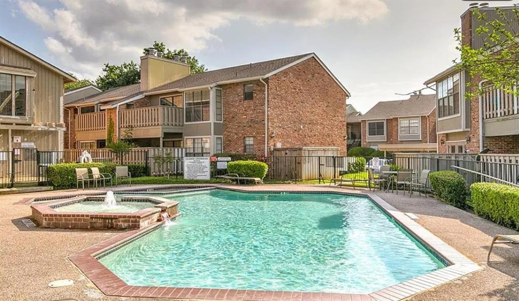 Community swimming pool with an integrated spa, surrounded by a paved deck and manicured hedges