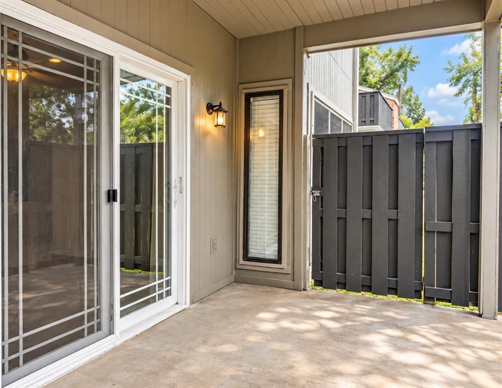 Private patio with concrete flooring, sliding glass door, white trim, and a privacy fence