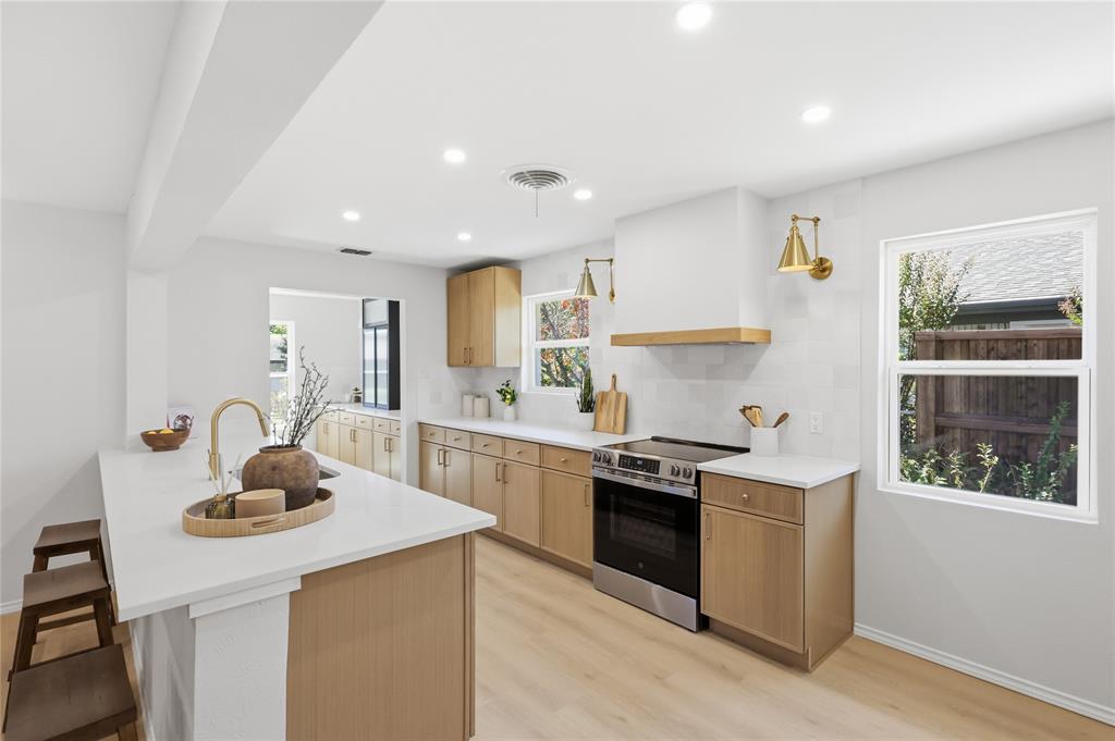 Kitchen featuring wood-finish cabinetry, quartz countertops, a matching hood vent, stainless steel range, and recessed lighting Kitchen featuring wood-finish cabinetry, quartz countertops, a matching hood vent, stainless steel range, and recessed lighting