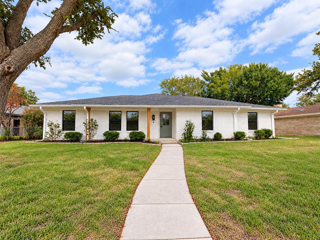 Single-story residence featuring a painted brick exterior, dark asphalt shingle roof, concrete walkway, and wood-wrapped front porch pillars