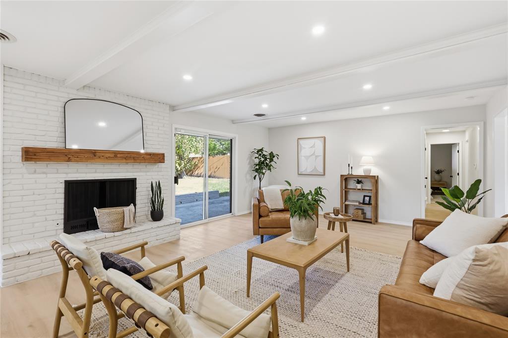 Living area featuring painted white brick fireplace, natural wood mantel, wood-finish flooring, ceiling beams, and recessed lighting Living area featuring painted white brick fireplace, natural wood mantel, wood-finish flooring, ceiling beams, and recessed lighting