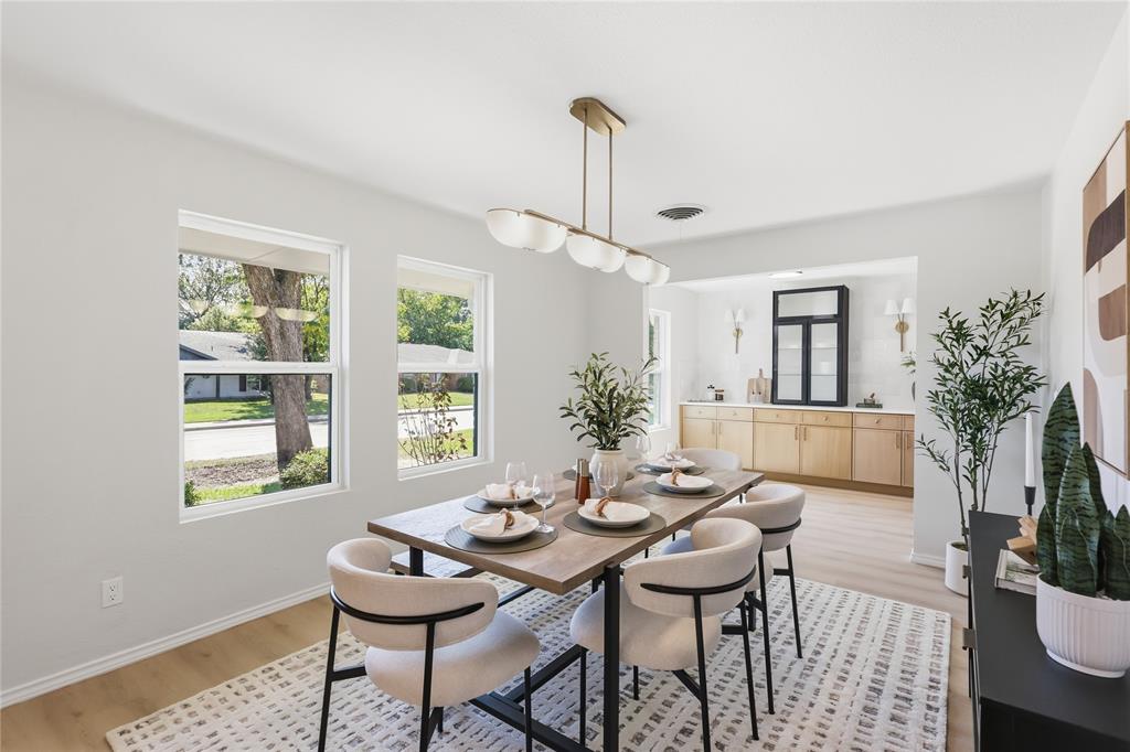 Dining area featuring wood-finish flooring, dual-pane windows, a linear multi-light pendant fixture, and a built-in cabinetry unit with a glass-front display cabinet