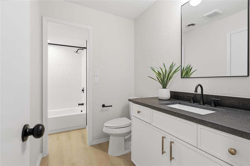 Bathroom featuring a white vanity cabinet with stone-finish countertop, under-mount rectangular sink, matte black fixtures, and a frameless wall-mounted mirror