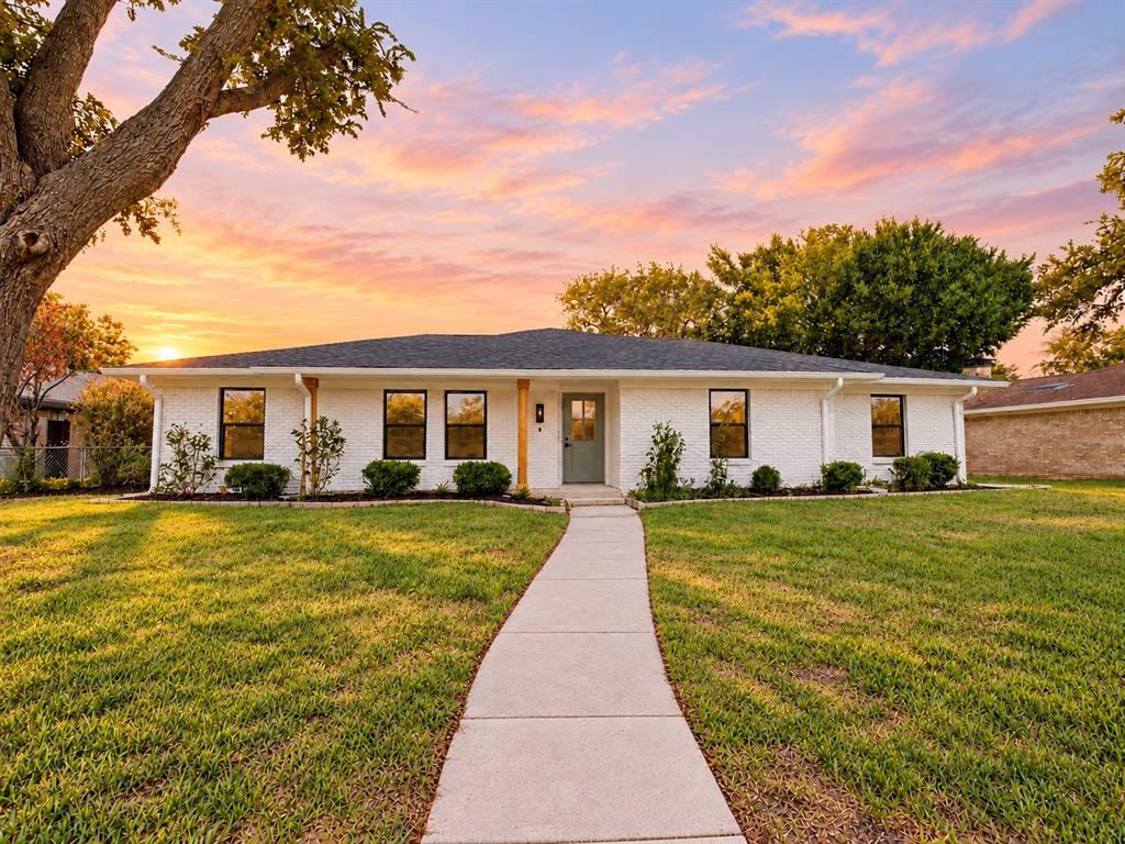 White painted brick exterior featuring a low-pitch roof, dark-framed windows, a centered entry door, and a concrete walkway White painted brick exterior featuring a low-pitch roof, dark-framed windows, a centered entry door, and a concrete walkway