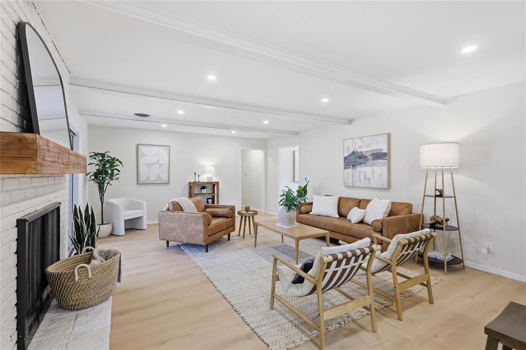 Painted brick fireplace with a natural wood mantel, wood-finish flooring, recessed lighting, and exposed ceiling beams Painted brick fireplace with a natural wood mantel, wood-finish flooring, recessed lighting, and exposed ceiling beams