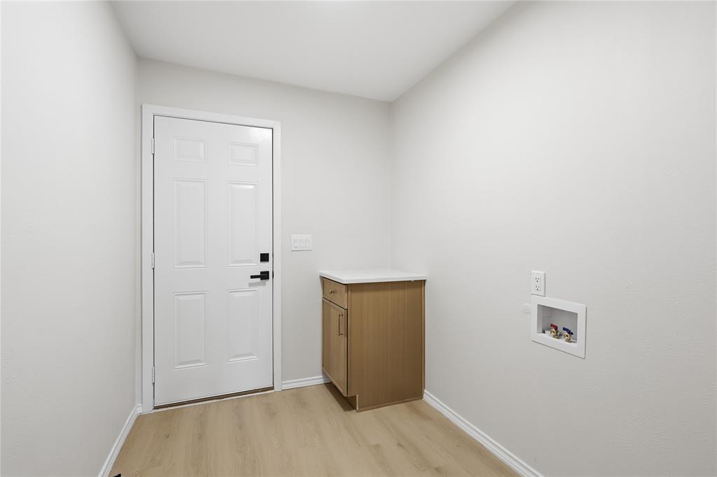 Utility room featuring wood-finish flooring, a built-in cabinet with a solid surface countertop, and dedicated washer and dryer hookups
