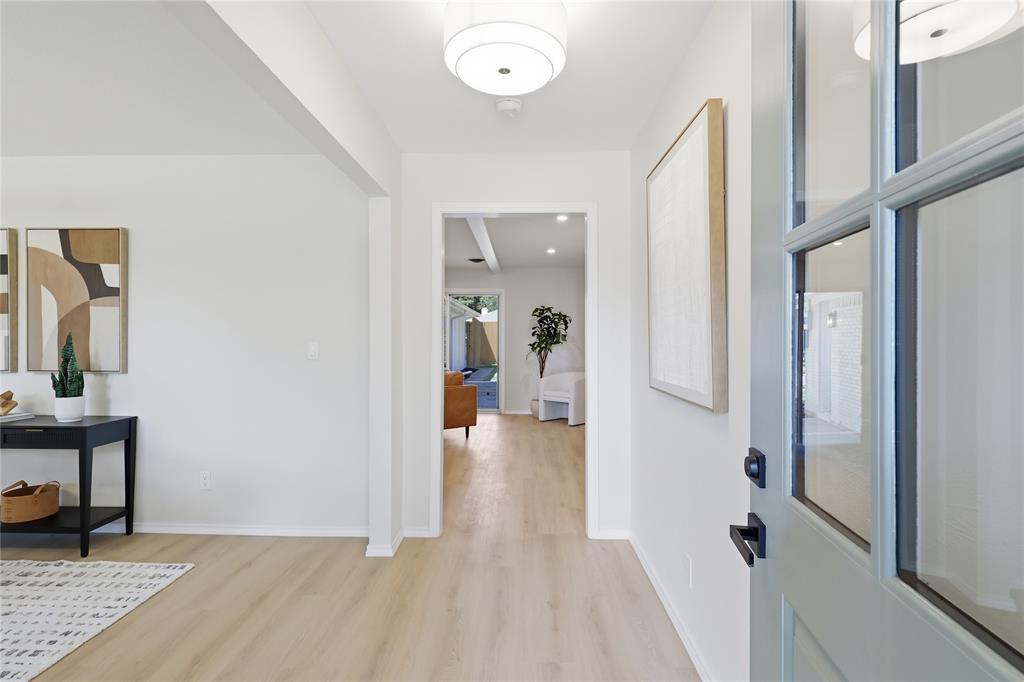 Entryway featuring light-toned wood-finish flooring, a multi-pane glass-inset door, and a modern drum pendant light fixture Entryway featuring light-toned wood-finish flooring, a multi-pane glass-inset door, and a modern drum pendant light fixture