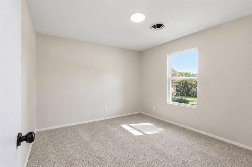 Neutral interior featuring light-toned wall paint, plush carpeting, a single-hung window, and a flush-mount overhead light fixture