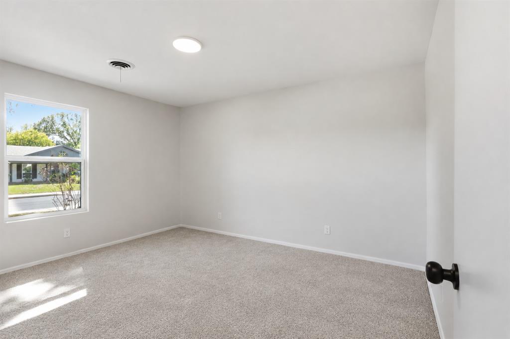Neutral-toned interior space featuring wall-to-wall carpeting, a flush-mount ceiling light fixture, and a single-pane window with exterior exposure