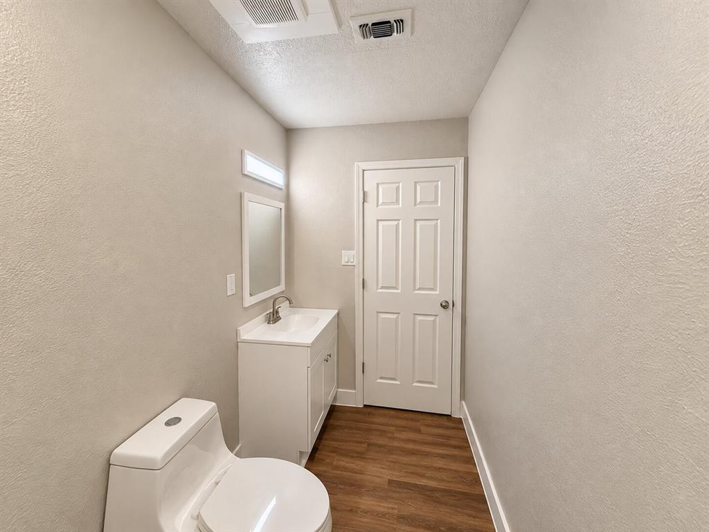 White vanity with an integrated sink, framed mirror, and wood-finish flooring White vanity with an integrated sink, framed mirror, and wood-finish flooring