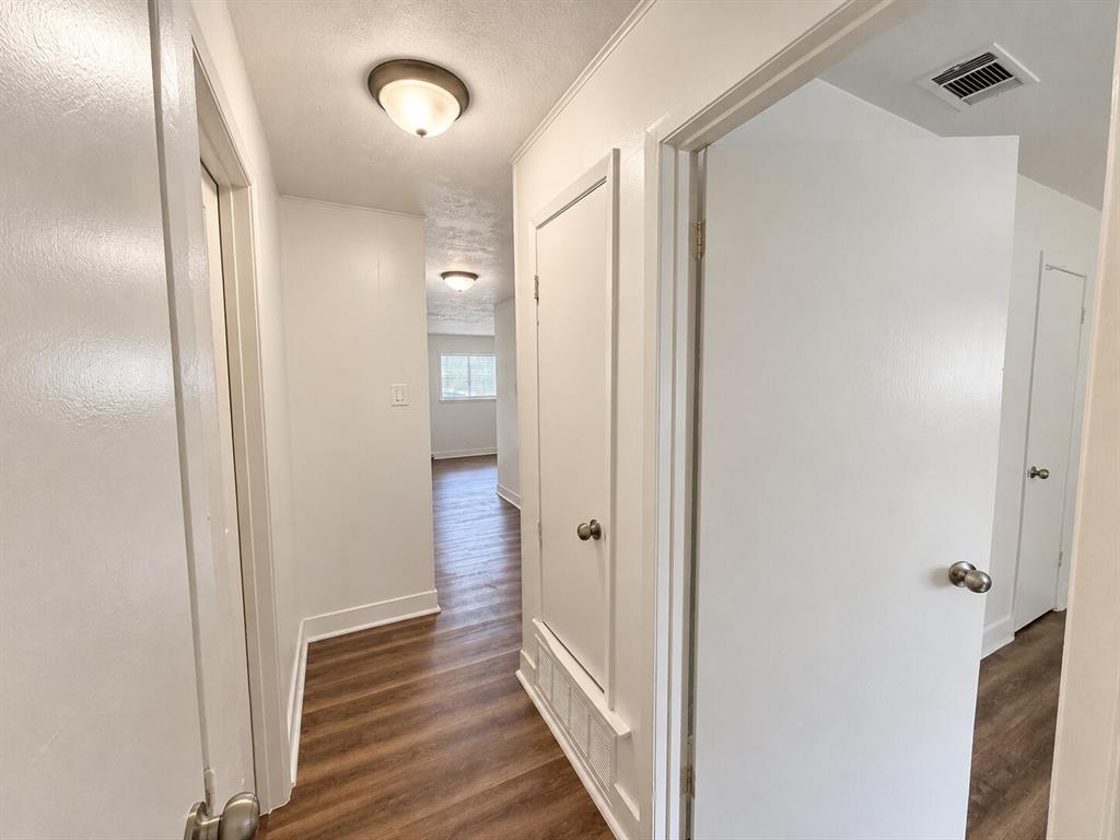 Hallway featuring wood-finish flooring, white walls, and flush-mount lighting fixtures