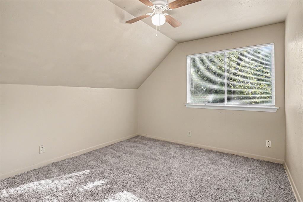 Sloped ceiling room featuring a ceiling fan, recessed window with blinds, and gray carpeting