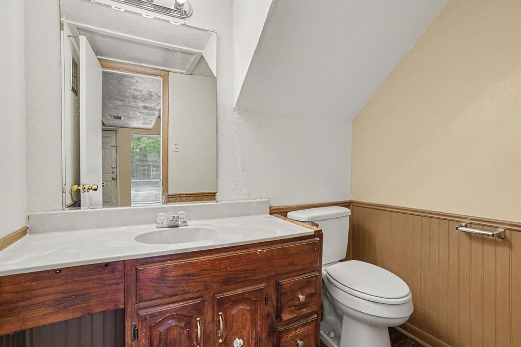 Vanity with a white countertop and integrated sink, wood-finish cabinetry, and a wall-mounted mirror