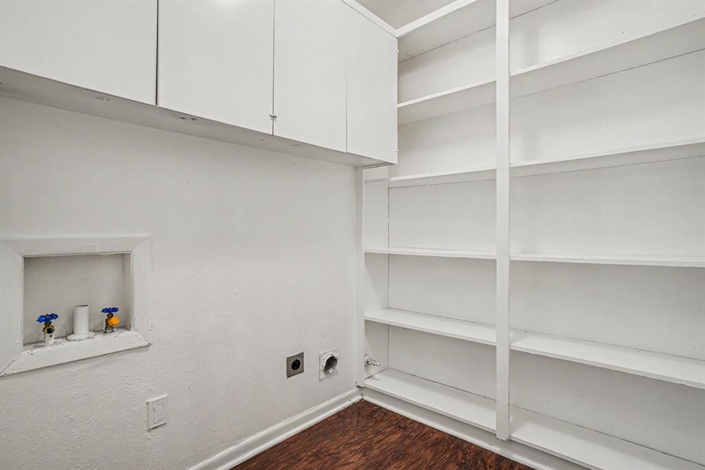White built-in cabinetry, extensive built-in shelving, wood-finish flooring, and laundry hookups
