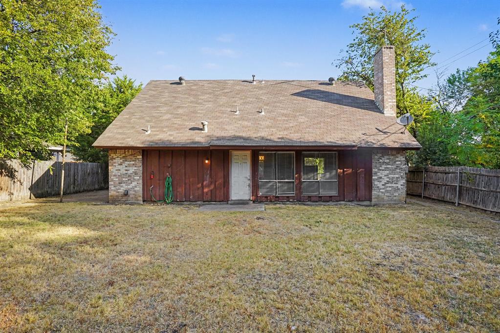 Expansive backyard featuring a wood fence, mature trees, and a brick chimney