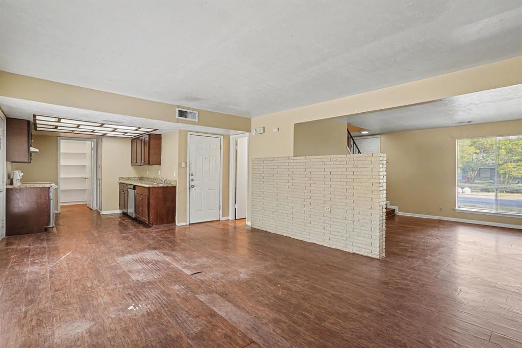 Wood-finish flooring throughout, with a kitchen area featuring wood cabinetry, a built-in dishwasher, and granite-style countertops