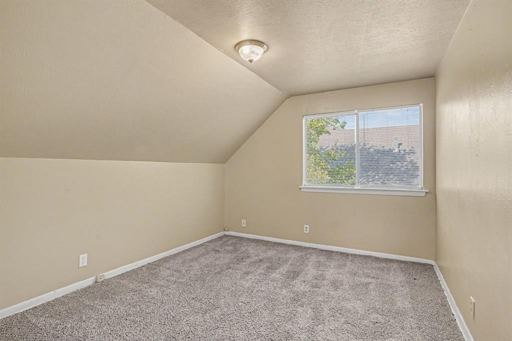 Sloped ceiling room featuring carpet flooring and a window with blinds