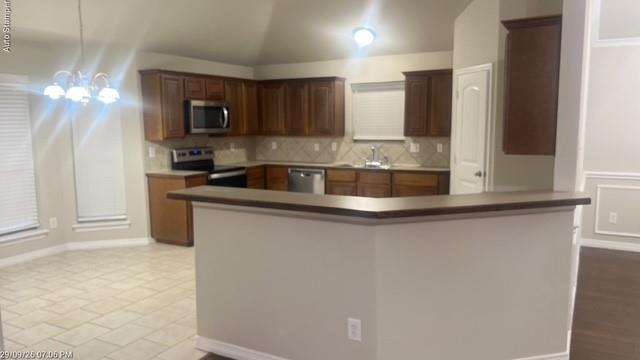 Kitchen featuring wood-finish cabinetry, stainless steel appliances, tile backsplash, and a breakfast bar