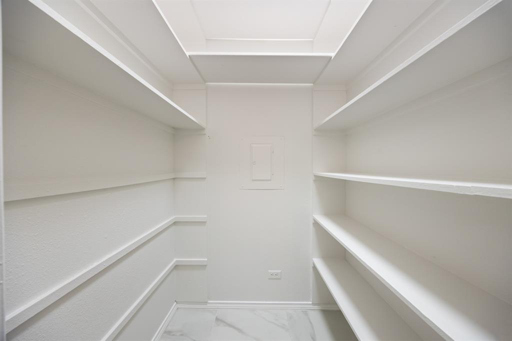 Recessed ceiling with integrated lighting, extensive built-in shelving, textured wall finish, and marble-look flooring