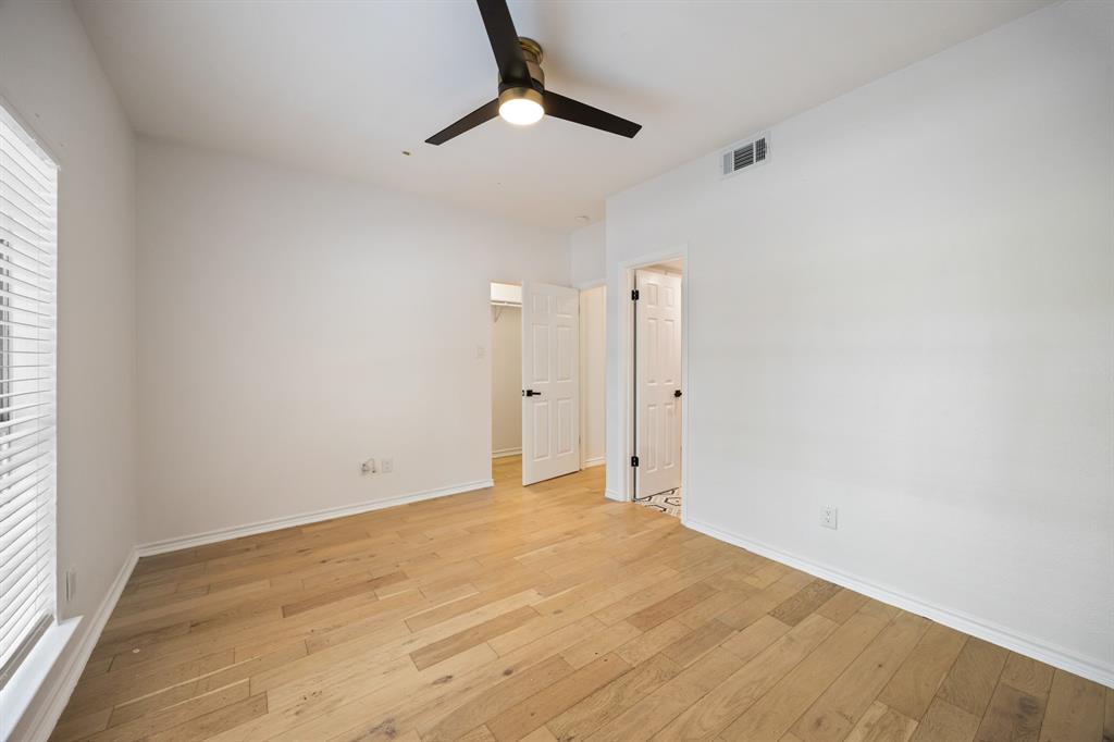 Light wood-finish flooring, white walls, and a ceiling fan with integrated lighting