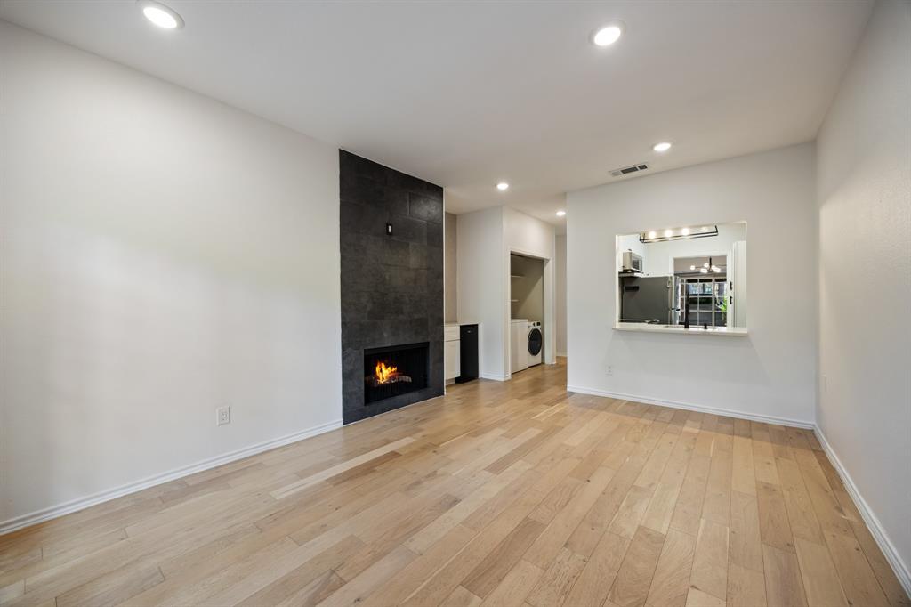 Wood-finish flooring, recessed lighting, and a modern fireplace with a dark stone-look surround