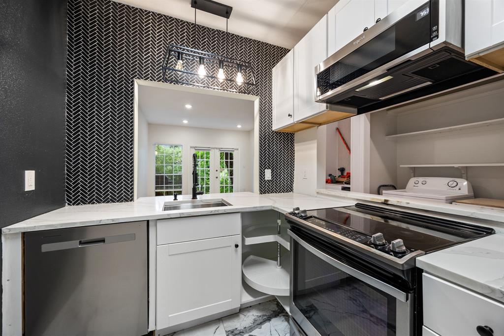 Kitchen featuring white cabinetry, light countertops, stainless steel appliances, and a black herringbone tile accent wall