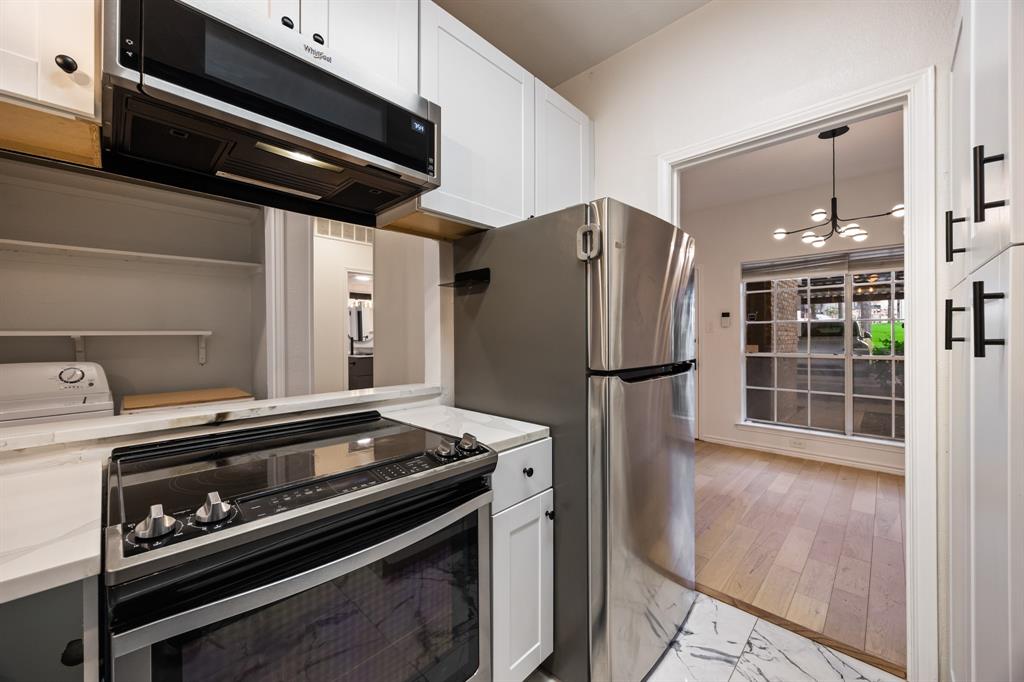White cabinetry, stainless steel appliances, electric range, quartz countertops, and marble-finish tile flooring
