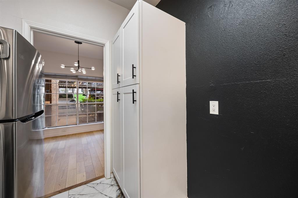 Stainless steel refrigerator, white shaker-style cabinetry with black hardware, and patterned floor tile