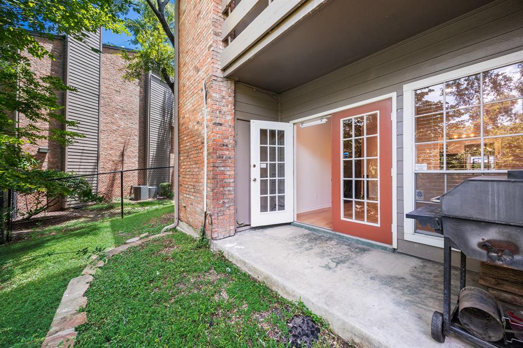 Private patio with concrete surface, double French doors, large windows, and a brick exterior accent