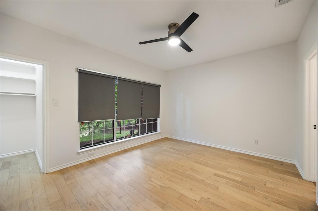 Light wood-finish flooring, a contemporary ceiling fan, and a built-in closet with shelving