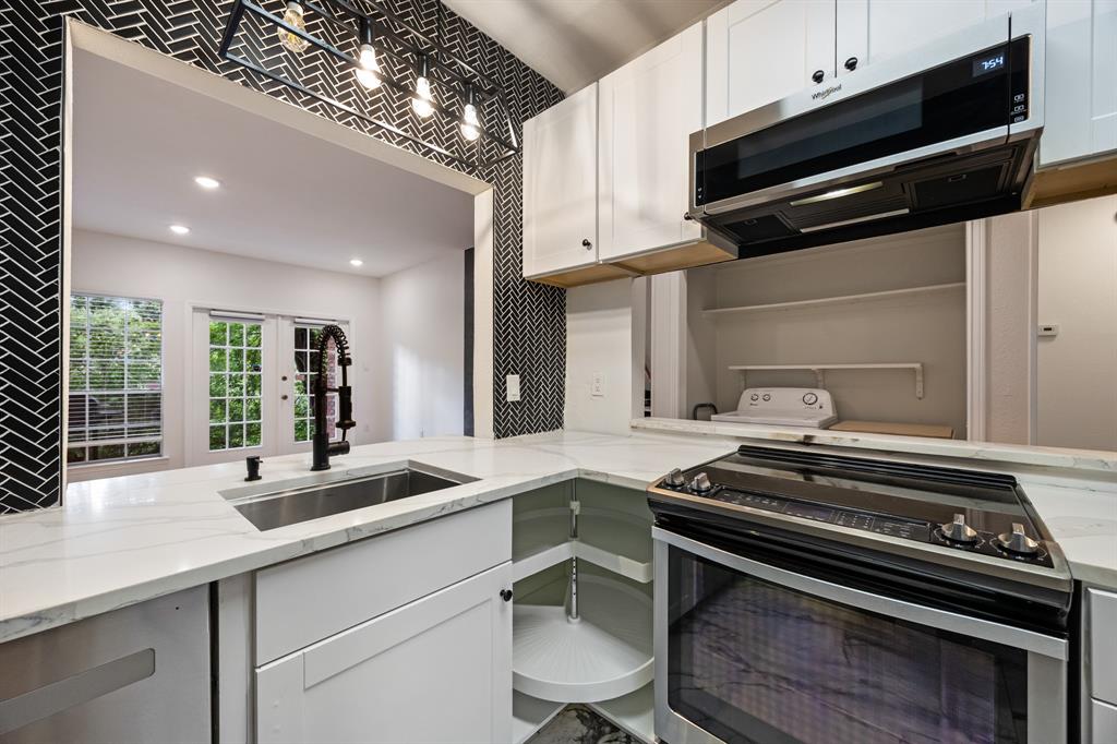 White shaker cabinetry, stainless steel sink, black herringbone tile backsplash, white countertops, and contemporary overhead lighting