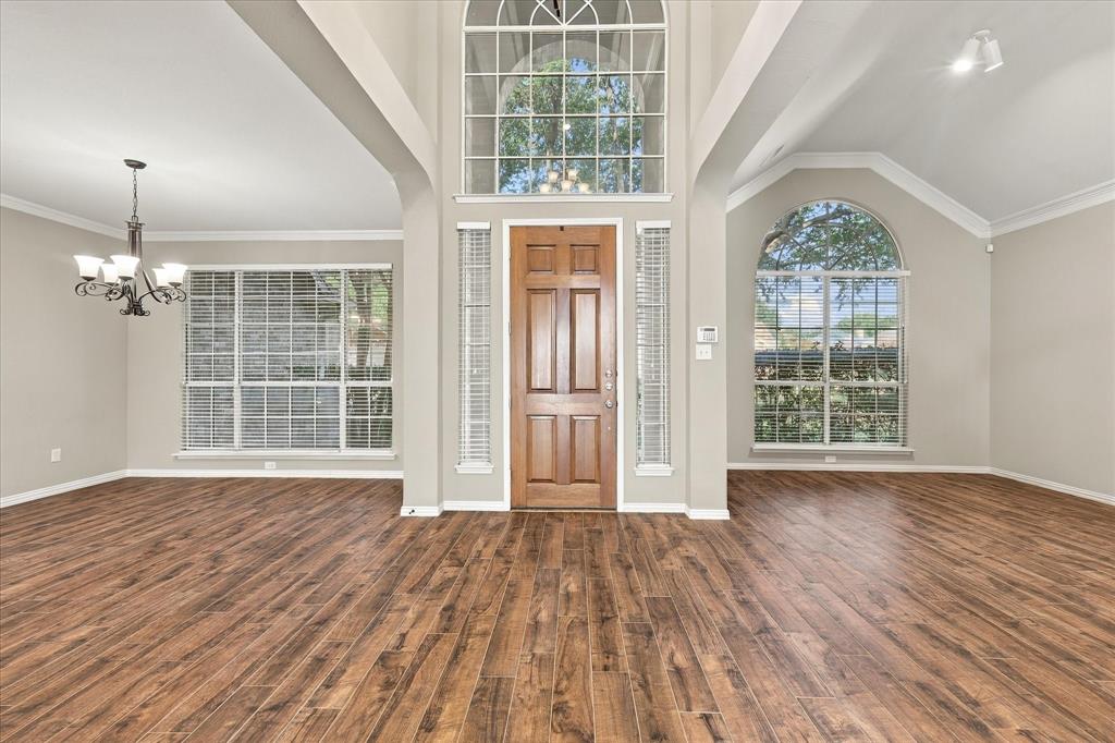 PREPARE TO BE IMPRESSED! Soaring ceilings, an extraordinary oversized arched window, elegant wood-look tile flooring, and graceful architectural details create a dramatic entrance flooded with natural light. Formal living/study and dining spaces frame this stunning grand foyer.